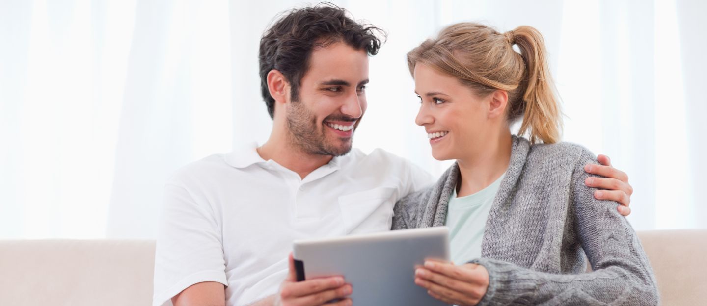 Young,Couple,Using,A,Tablet,Computer,In,Their,Living,Room